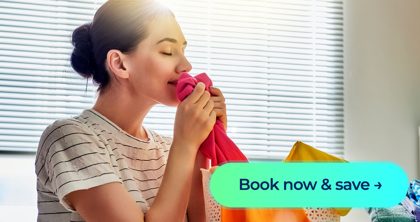 A woman holds a freshly laundered shirt near a laundry basket with a “Book now & save” button overlay