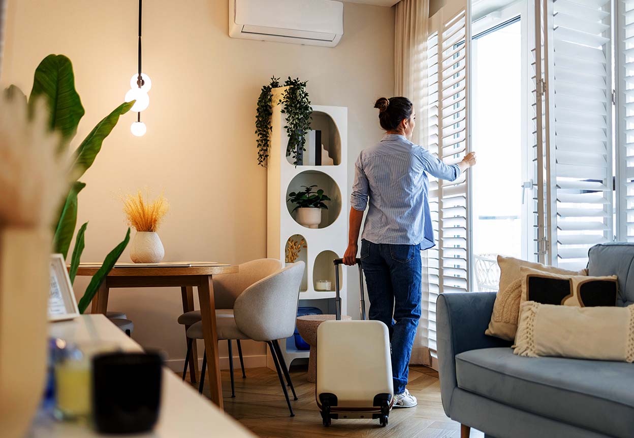 Person opening window shutters before leaving home with a suitcase