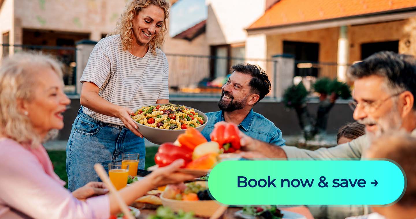Woman serves pasta salad at an outdoor family meal with a “Book now & save” button.