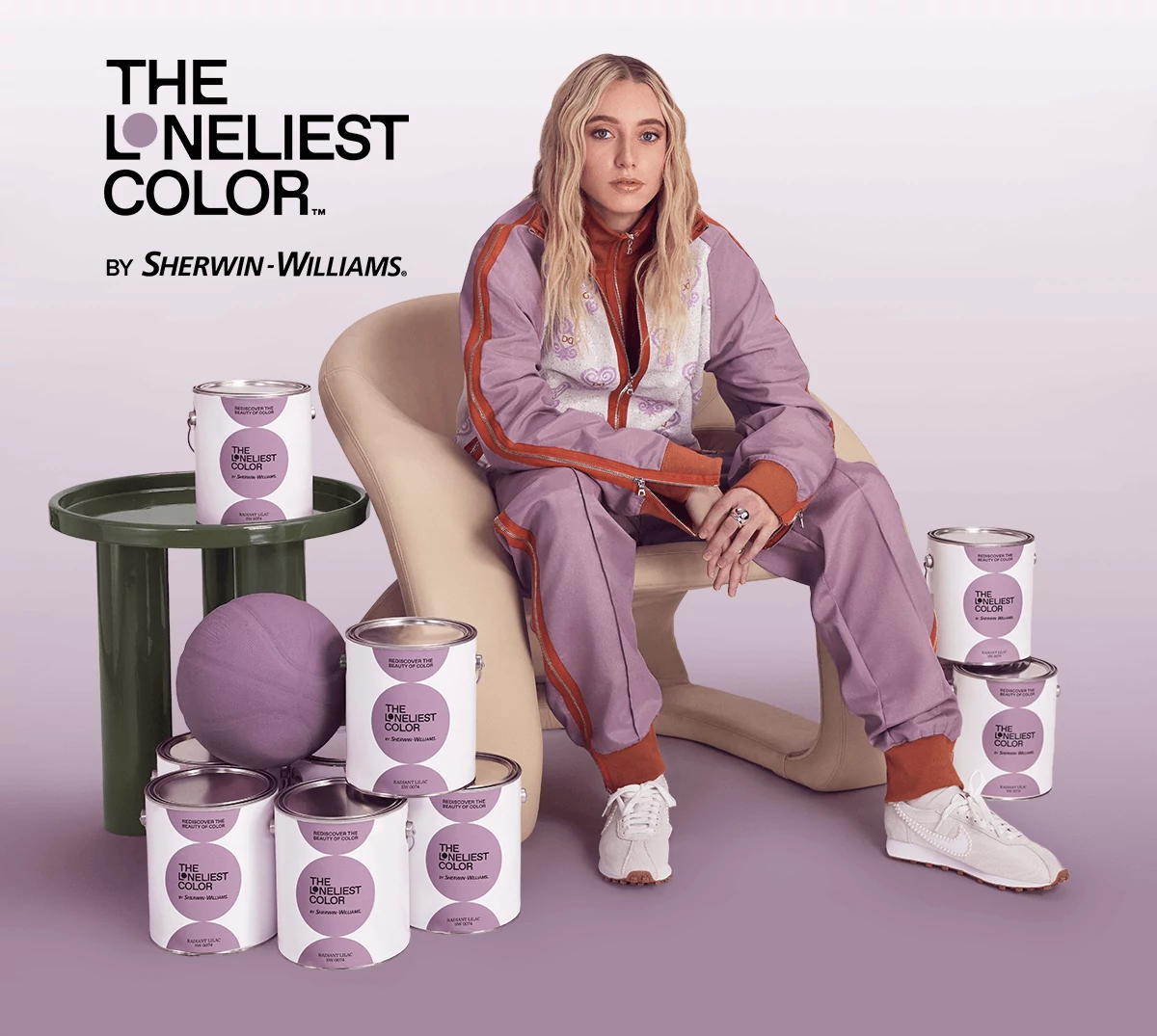 The Loneliest Color by Sherwin-Williams. Paige Bueckers sitting in a modern chair surrounded by The Loneliest Color paint cans.