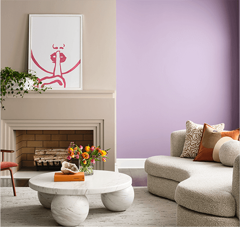 Living room with neutral modern sofa, coffee table and fireplace. Wall painted in Radiant Lilac.