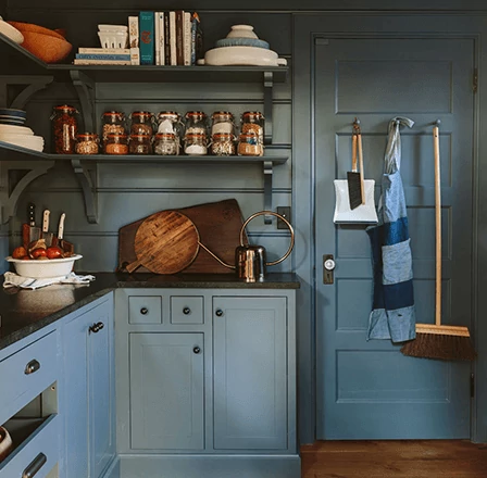 Moody kitchen, with filled open air shelves and wood cutting boards, painted in Slate Tile.