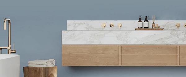 White bathtub, stool, with bath towels on top, and floating counter with brass hardware in bathroom painted in Daphne.