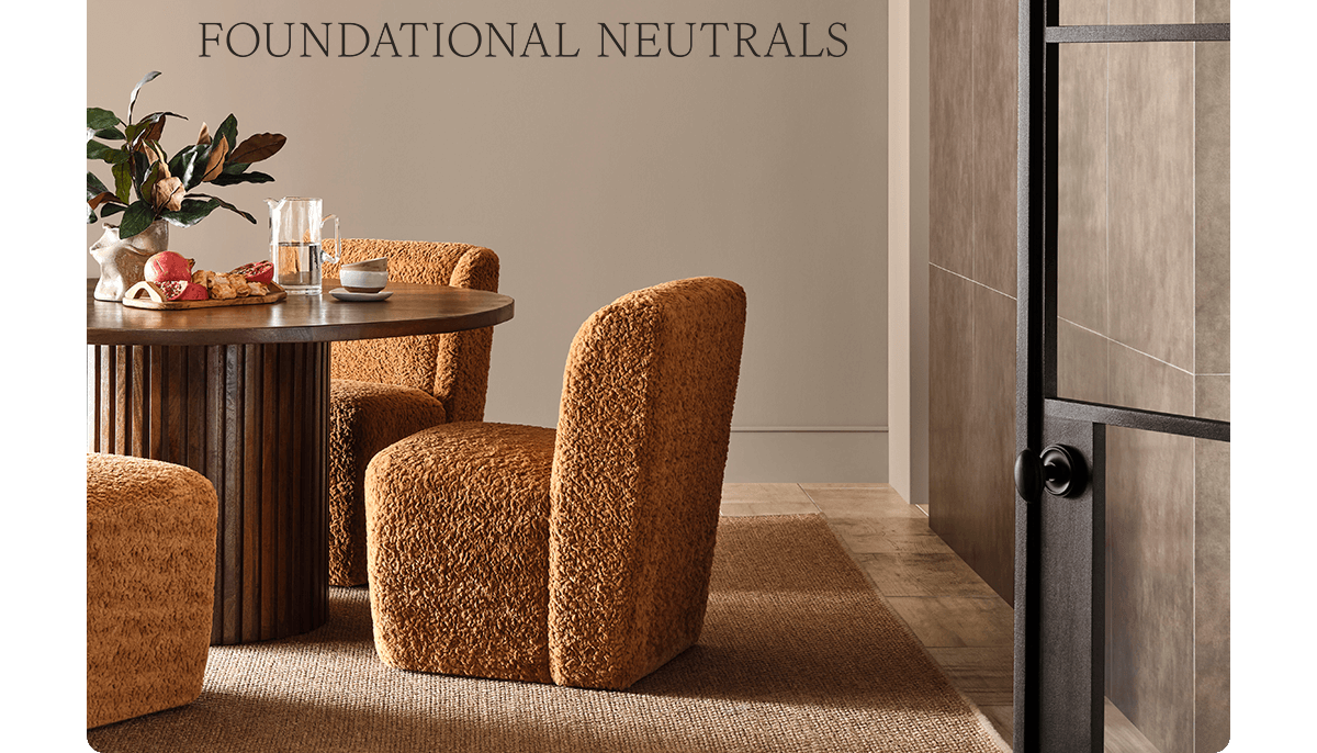 Dining room painted in Sanderling with cozy chairs next to round wooden table with breakfast spread and tiled accent wall.