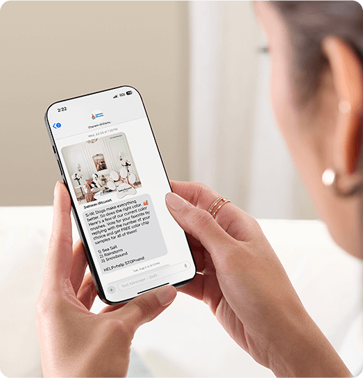 Woman looking at smartphone with Sherwin-Williams app on the screen.