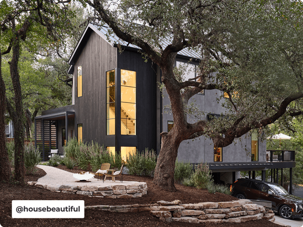 Exterior of modern cedar-sided and concrete home in wooded enviroment. Courtesy of @housebeautiful.