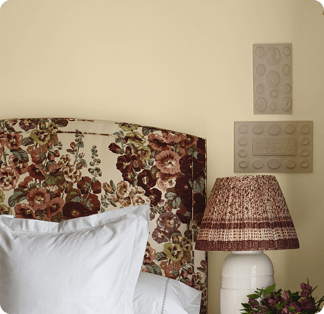 Floral bed headboard with white pillows in Lemon Chiffon painted room.