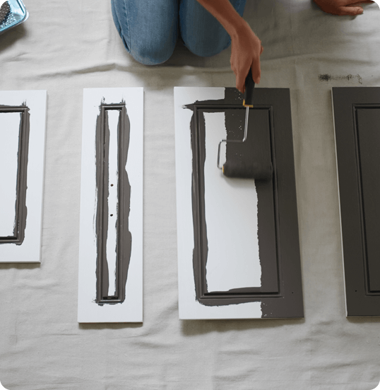 Person painting cabinet doors with roller.