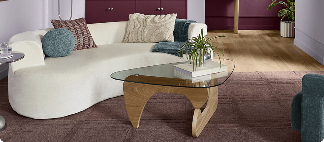 Organic white sofa & light wood base with glass top coffee table in trendy living room painted in Grape Mist.