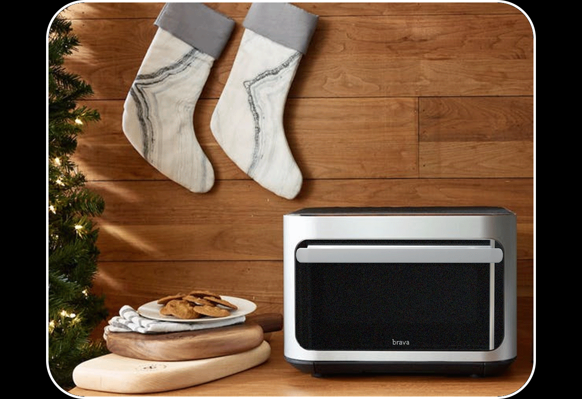 Brava Glass glowing on and off beside a twinkling Christmas tree, stockings, and a plate of chocolate chip cookies.