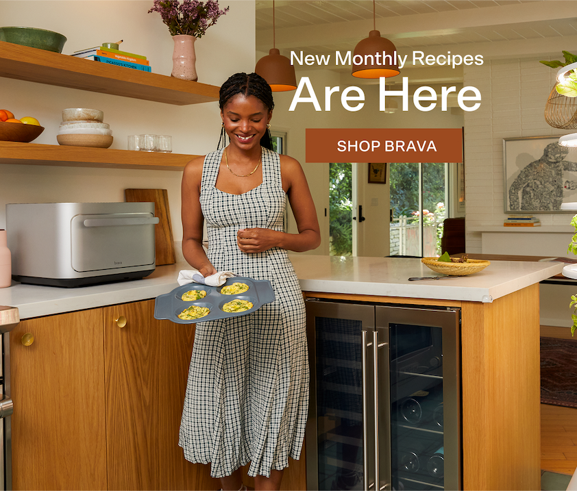 image of woman standing near brava in a nicely designed kitchen, holding brava egg tray with cooked egg bites