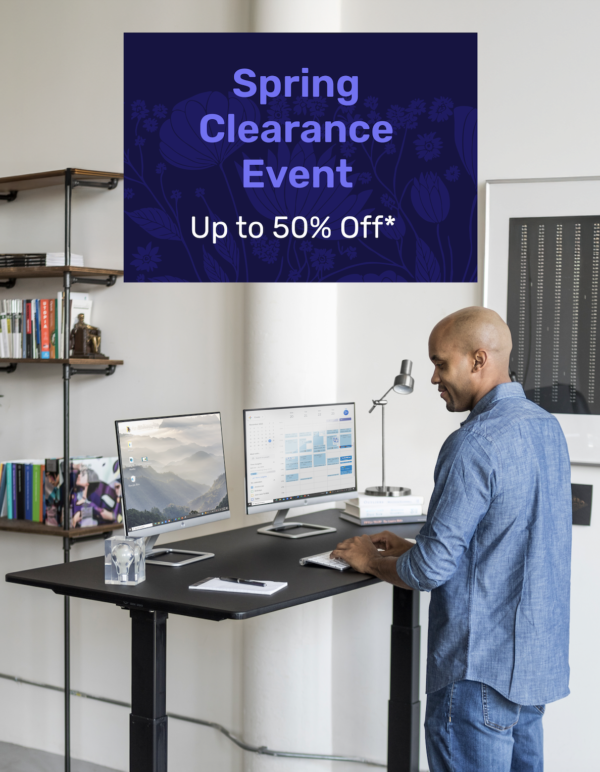 Man working at a standing desk in a bright office space. Promotional banner reads: 'Spring Clearance Event – Up to 50% Off*'