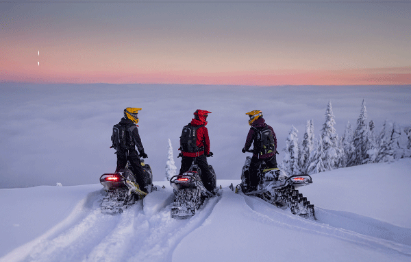 3 deep-snow riders on their snowmobile