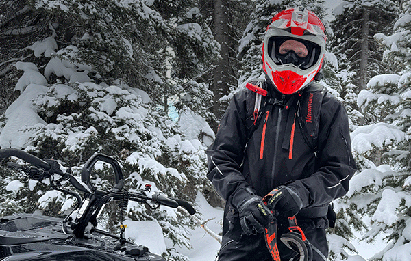 Ski-Doo rider standing next to a sled