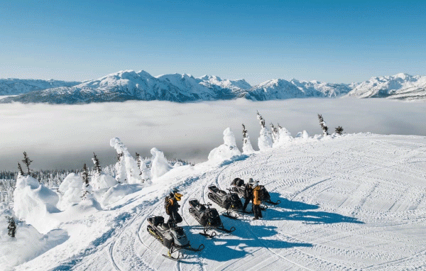 People on a mountain with Ski-Doo sleds
