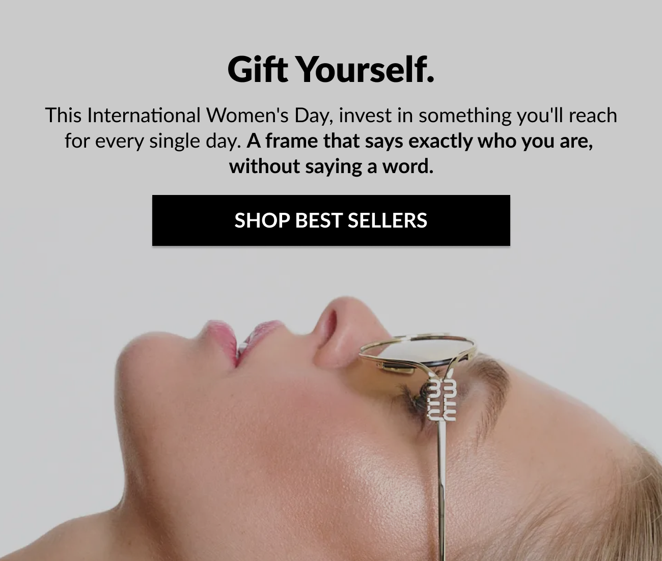 Hero section reads “Gift Yourself” with supporting copy encouraging shoppers to invest in a frame that reflects who they are this International Women’s Day, alongside a bold “Shop Best Sellers” call-to-action button. The image shows a close-up profile of a woman wearing gold designer sunglasses.