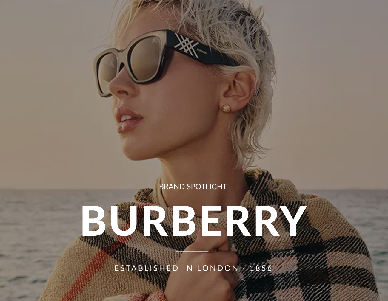 Hero image featuring a model wearing Burberry sunglasses with heading that reads, “Brand Spotlight: Burberry,” and subheading, “Established in London · 1856.”