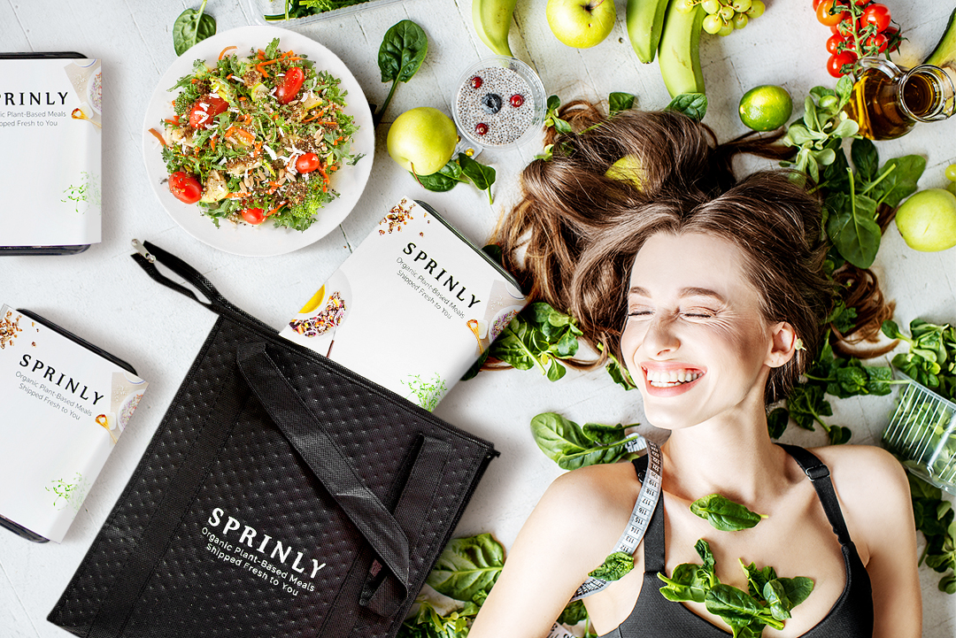 portrait of a happy woman surrounded by various healthy food and sprinly meal boxeslying on the floor. Healthy eating and sports lifestyle 