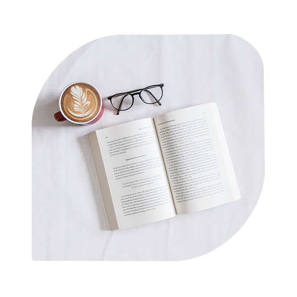 Coffee and Opened Book with Glasess on White Sheet
