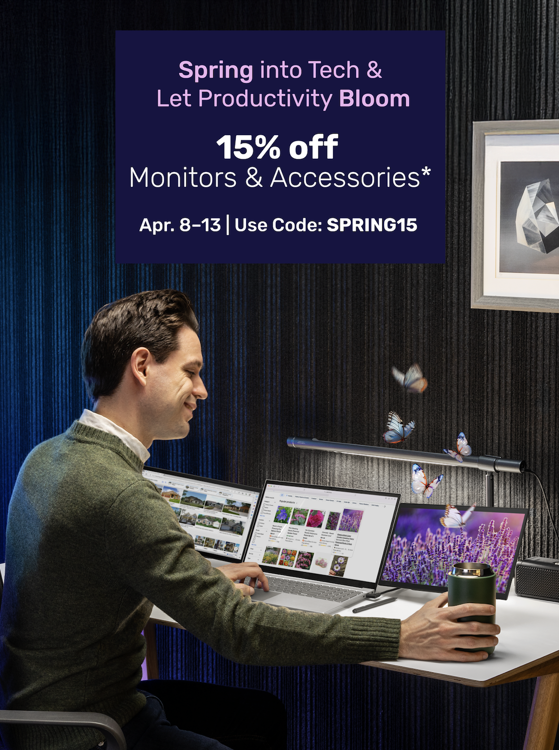 Man at desk using laptop and dual portable monitors with a green mug. Butterflies flutter near a desk lamp. Purple banner reads: 'Spring into Tech – 15% off Monitors & Accessories. Apr. 8–13 | Code: SPRING15'.