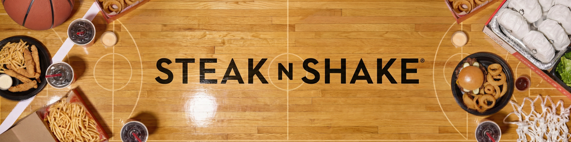 Full basketball court with Steakburger Box and other catering items. Basketball in upper left corner and net in lower right corner.