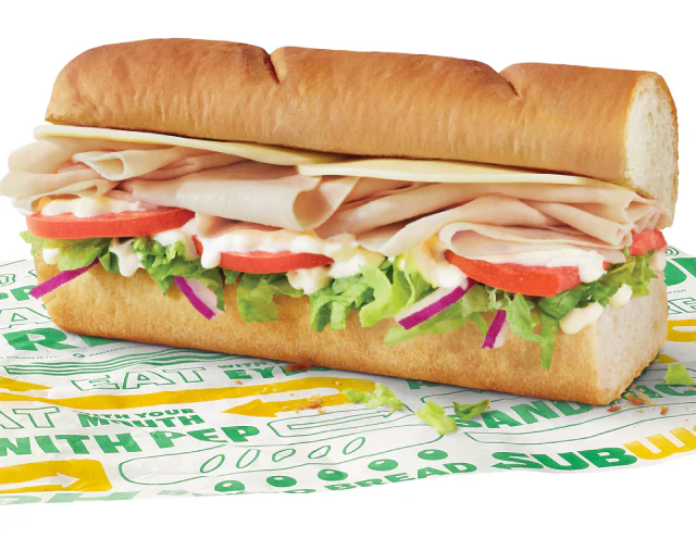 A 6" turkey and cheese sub sits atop Subway-branded paper.
