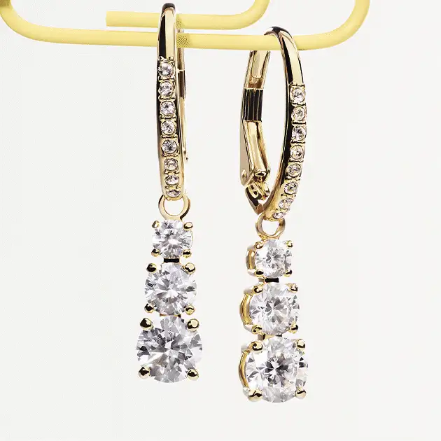 Swarovski earrings hang from a paperclip and a Swarovski bracelet rests on scissor handles