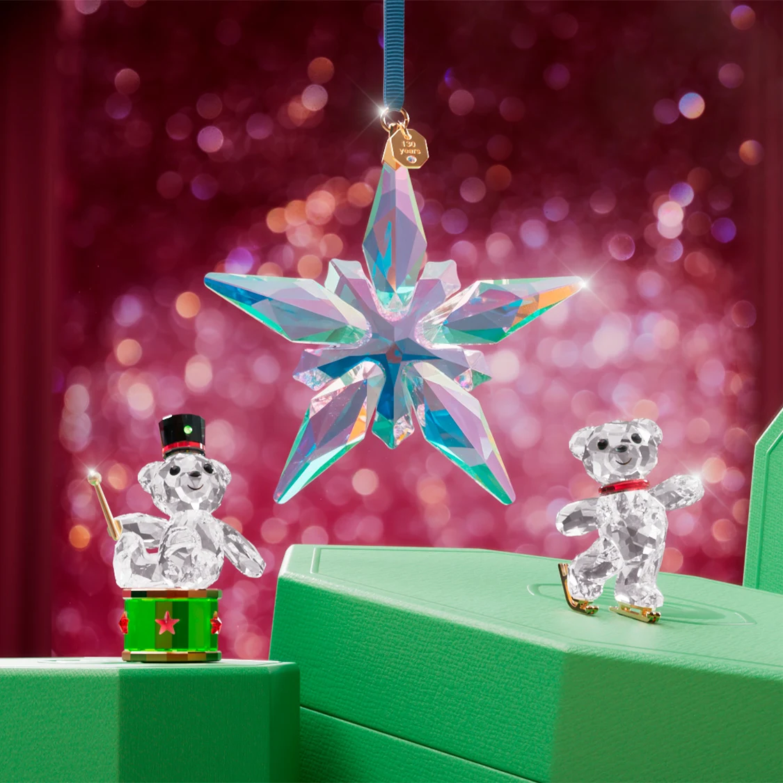 Swarovski Kris Bear figurines on green Swarovski gift boxes with the Annual Edition Ornament hanging above