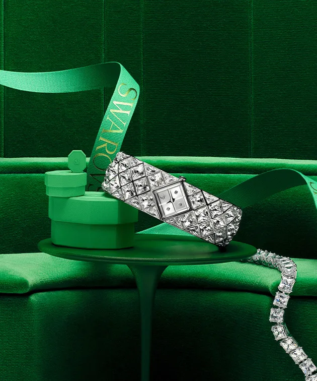 Swarovski watch and jewelry with a green gift box sitting on green table with green background