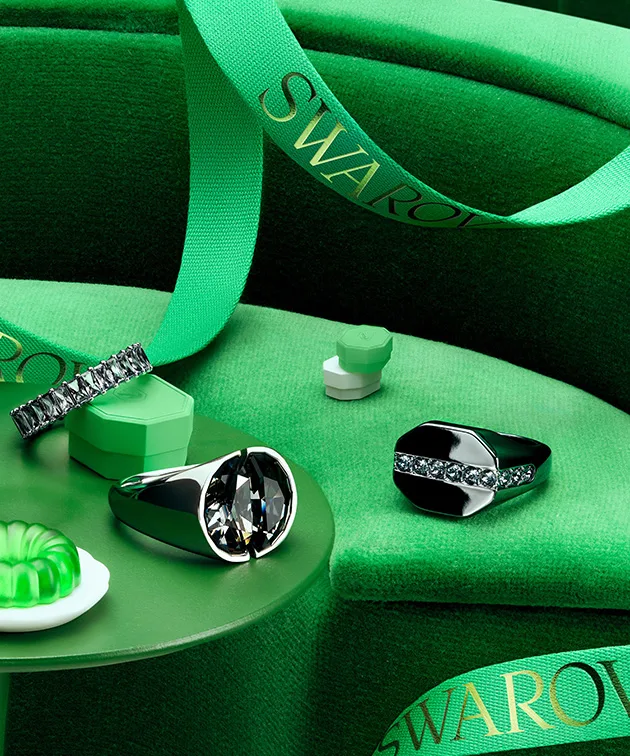 Swarovski jewelry and green gift box sitting on green table with green background