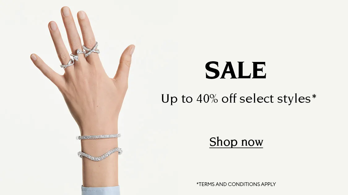 Hand and wrist wearing Swarovski jewelry. Text reads “SALE Up to 40% off select styles* Shop now *TERMS AND CONDITIONS APPLY”