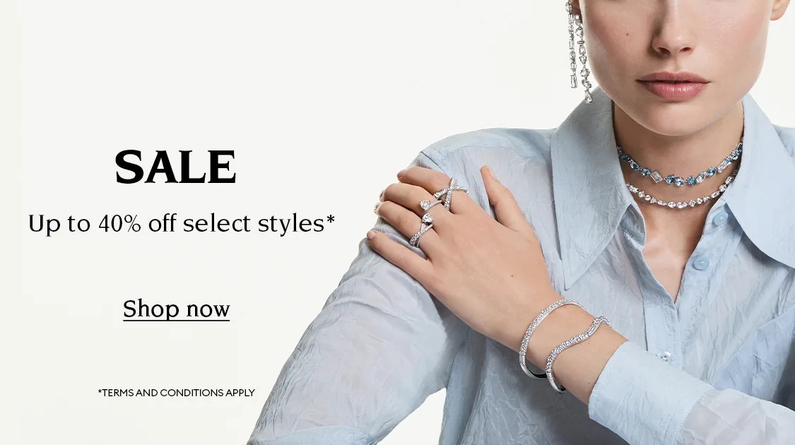 Model wears Swarovski jewelry. Text reads ‘SALE Up to 40% off select styles* Shop now *TERMS AND CONDITIONS APPLY’