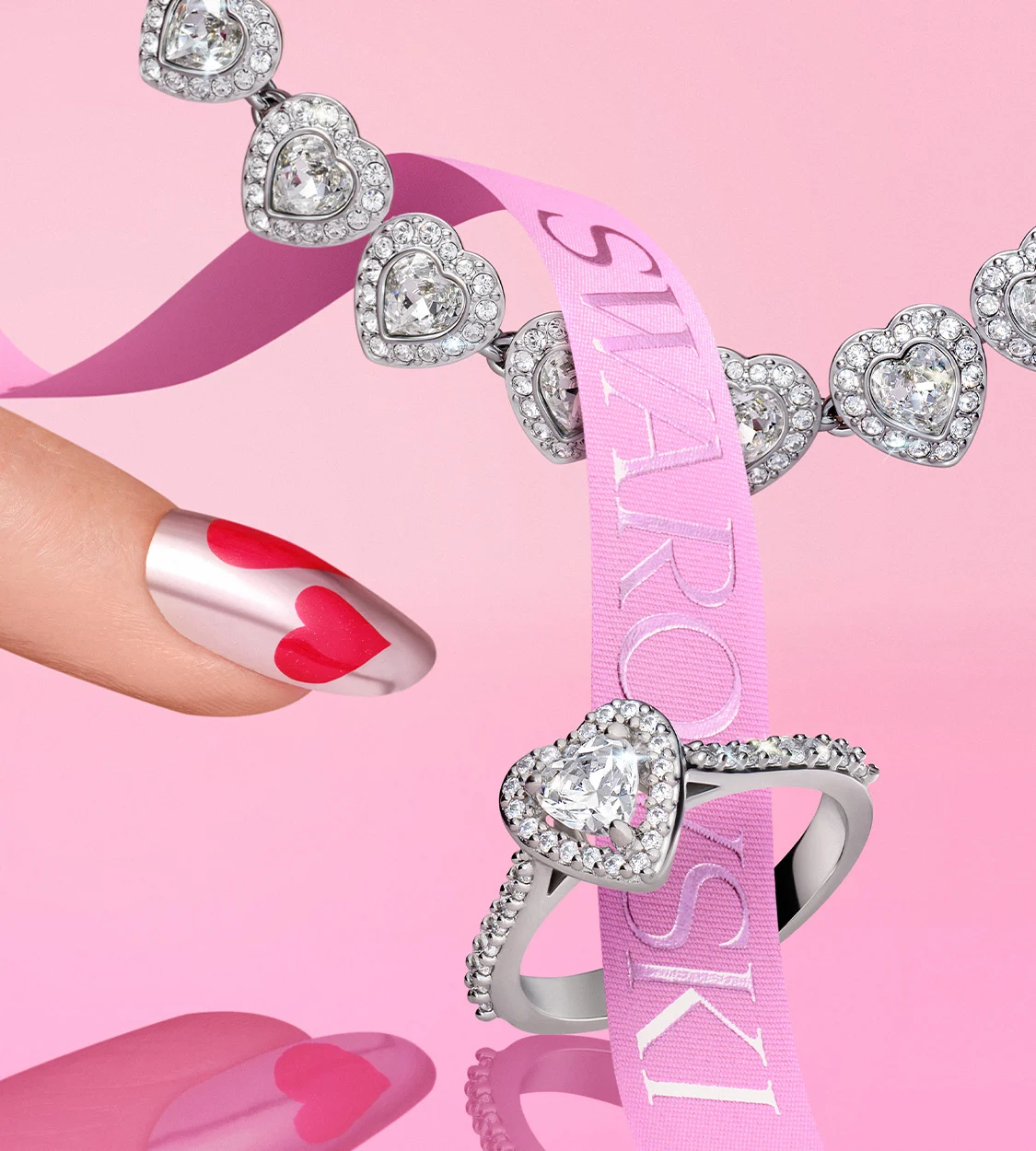 Fingernail with heart-shaped nail polish pointing at heart-shaped ring
