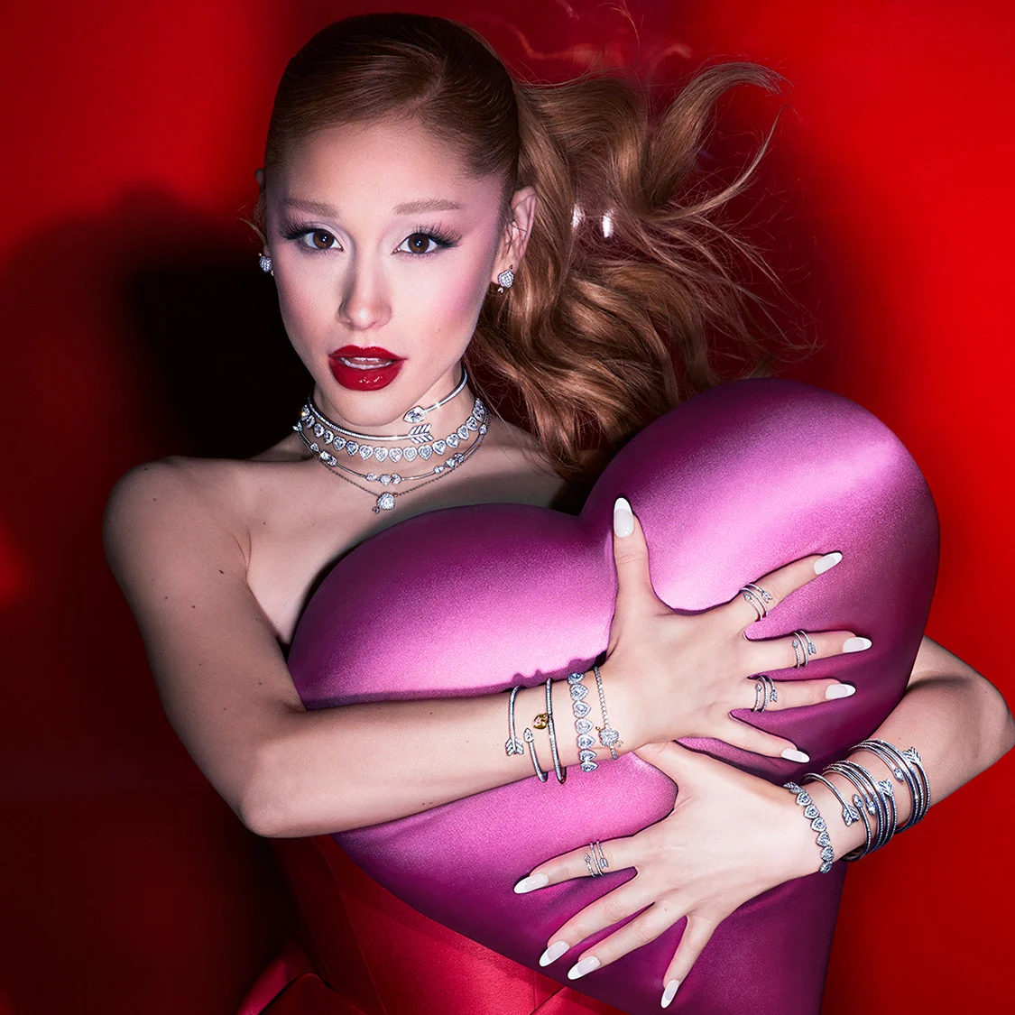 Ariana Grande wearing Swarovski Charms and jewelry while holding a pink heart