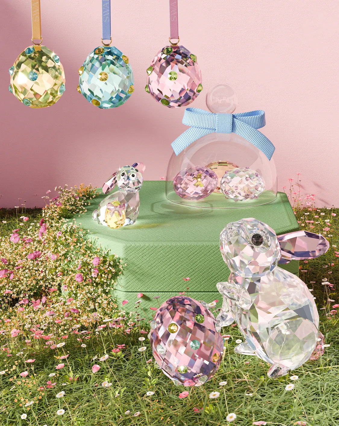 A group of small, colorful Swarovski  crystal figurines sit on a pink octagonal box.