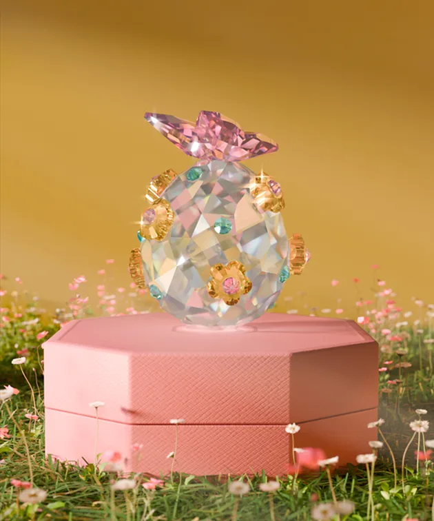 Faceted Swarovski crystal egg decorated with pink, blue, and gold accents, topped with a pink Swarovski crystal butterfly.