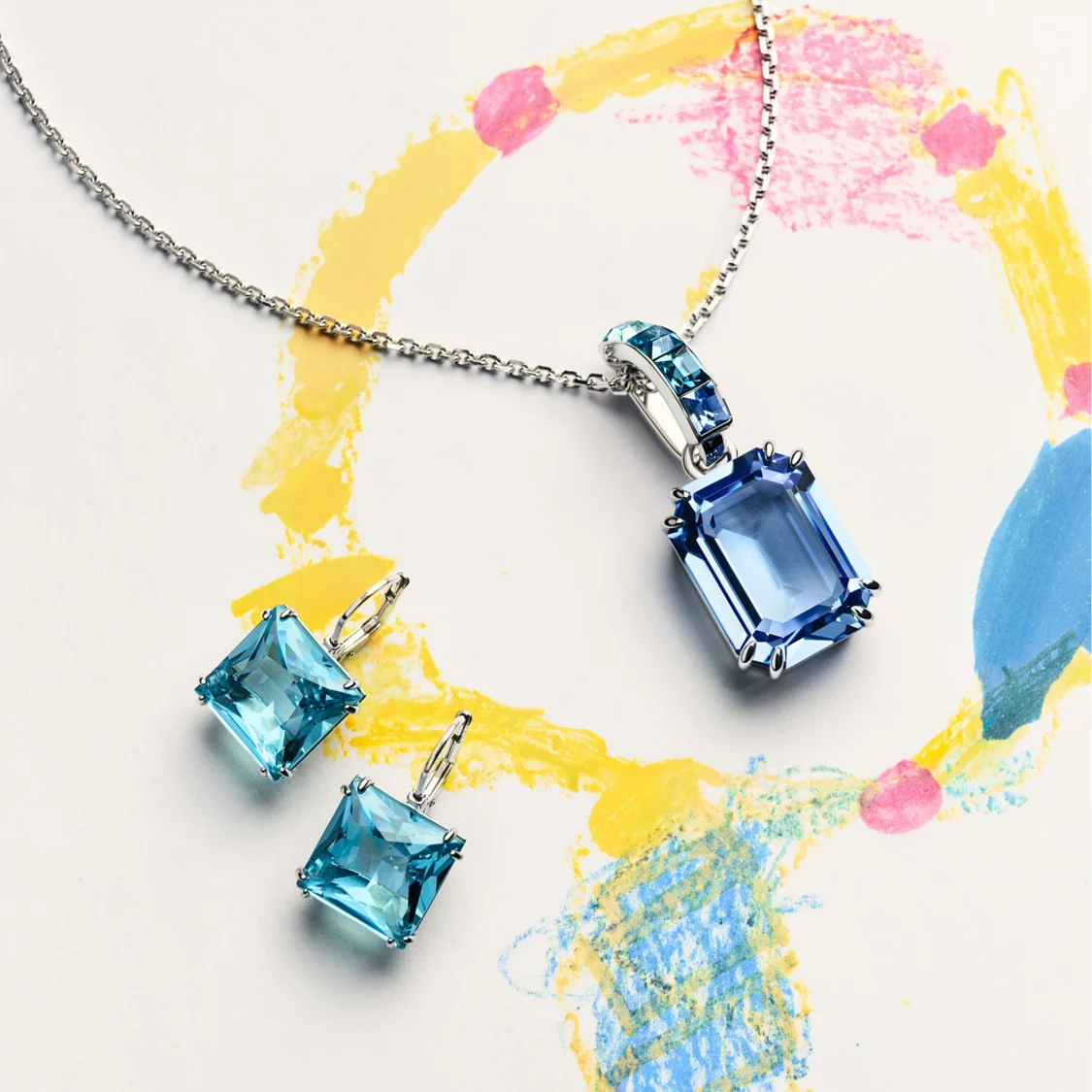 Blue Millenia pendant and earrings on childlike drawing