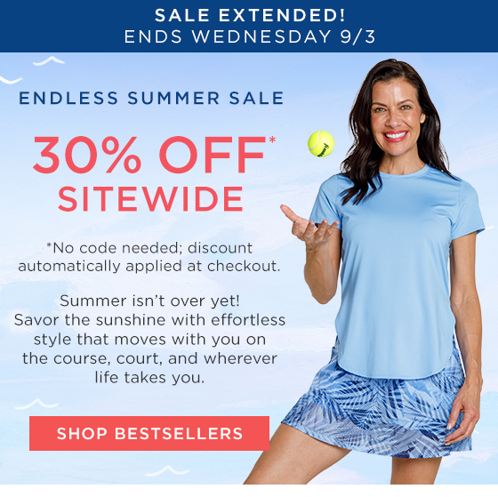 Woman in light blue short sleeve top with curved hem and tonal blue palm print skort