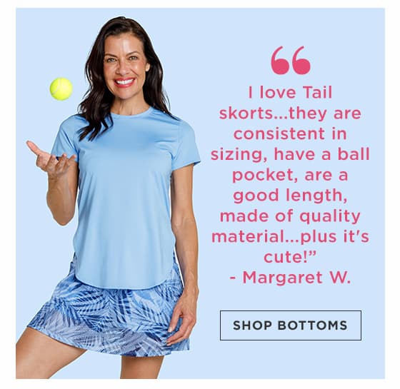 Woman in light blue short sleeve top with high-low hem and blue palm print skort