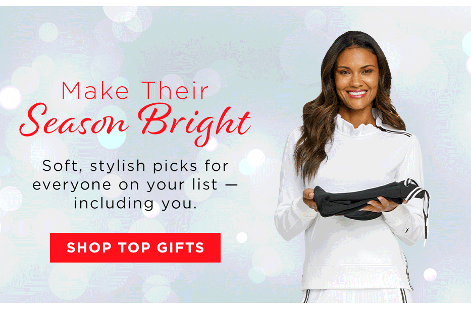 Woman in white long sleeve pullover with ruffle collar holding a stack of clothing