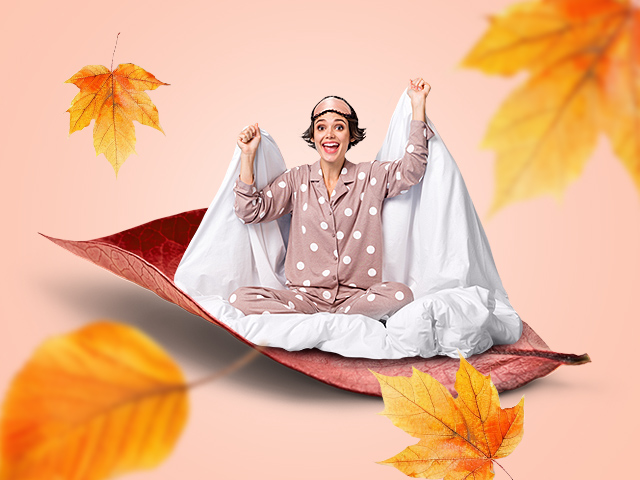 A lady wrapped in a blanket with autumn leaves around her