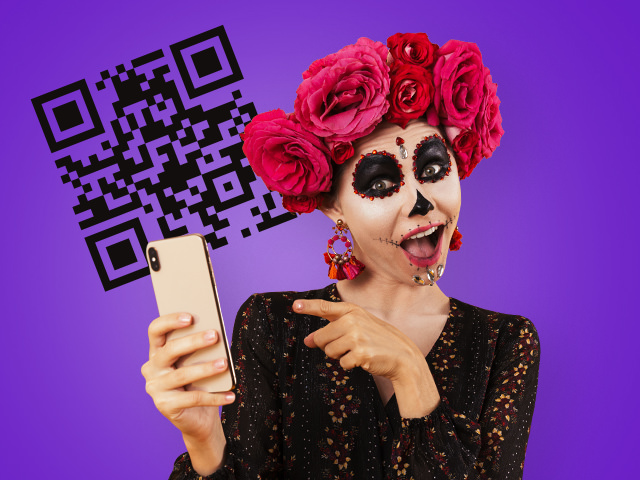 A girl with her face painted, holding a smartphone in her hand and pointing to it