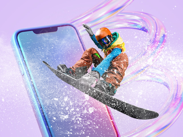 A man on a snowboard with a big phone in the background
