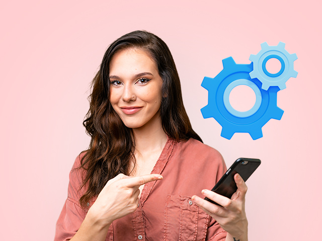 A woman smiling and pointing to the phone in her hand