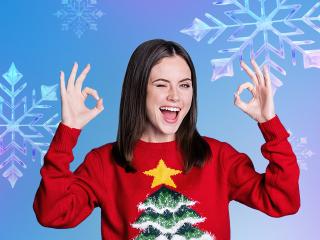 A cheerful woman wearing a Christmas sweater smiling and winking at the camera.