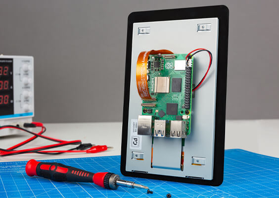 Rear of the Raspberry Pi Touch Display 2 with Raspberry pi 5 fitted, on a desk with tools and workmat
