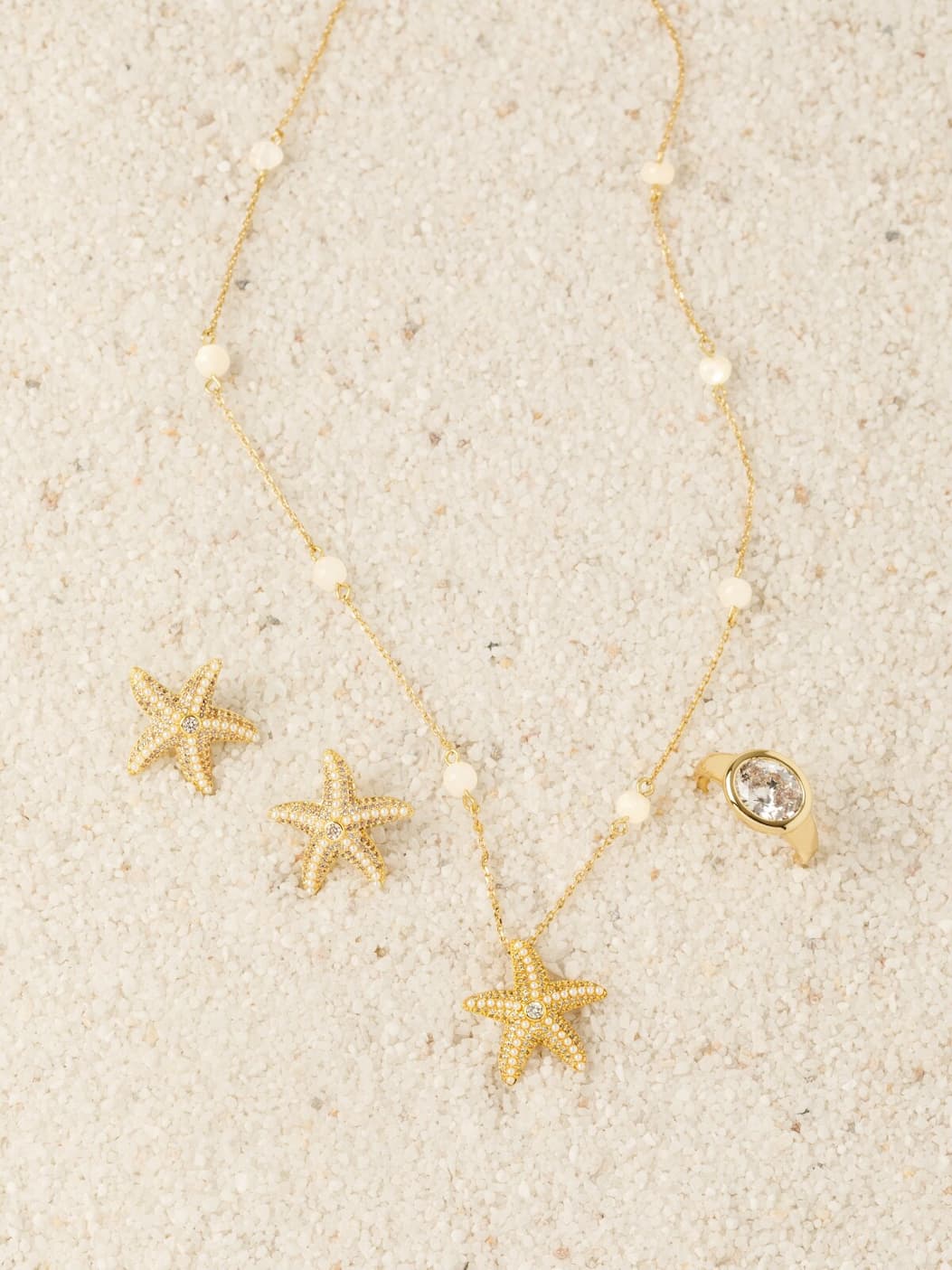 Beauty shot on sand of Starborn Pearl Station Necklace, Studs, and Shoreline Ring