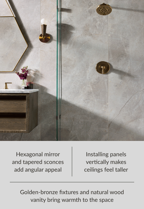 Golden-bronze fixtures and natural wood vanity bring warmth to the space. Installing panels vertically makes ceilings feel taller. Hexagonal mirror and tapered sconces add angular appeal