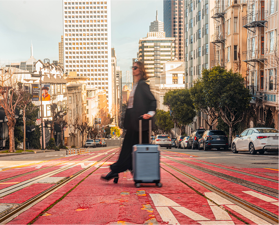 woman crossing the road in a city with her Travelpro suitcase