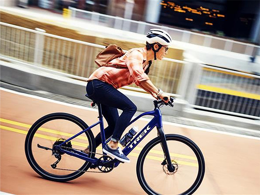 Cyclist wearing helmet while riding bike on paved road